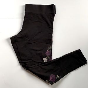 Black legging with flowers strip down each leg.